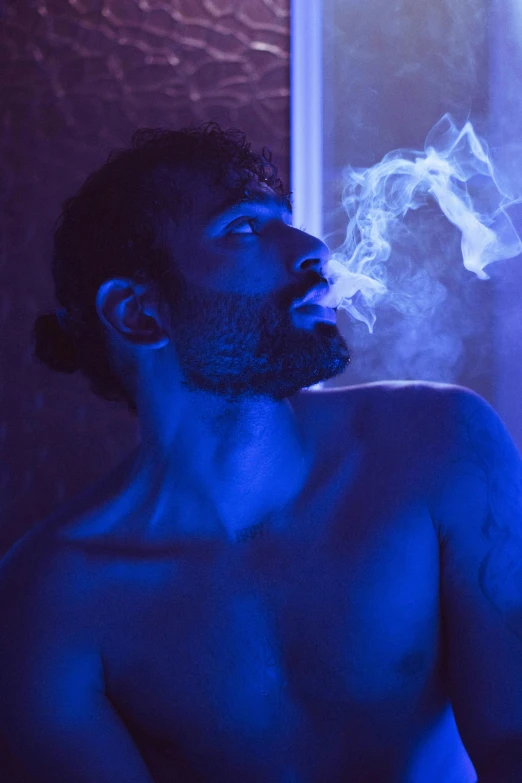 man smoking a cigarette in the dark with his arm spread