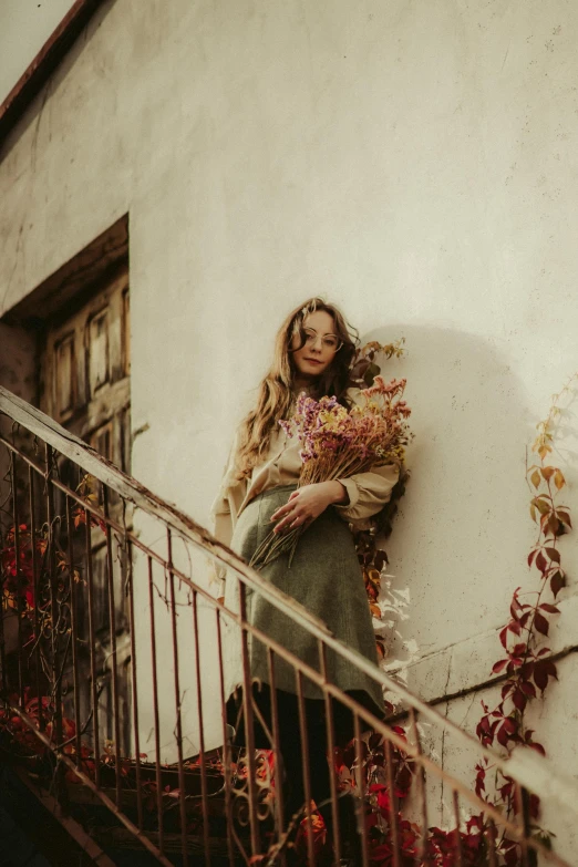 woman on stairs holding flowers leaning against a wall