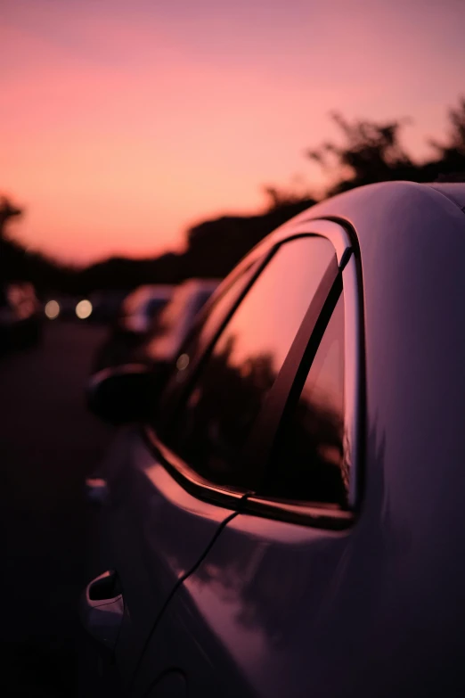 the sun is setting in the distance behind a car