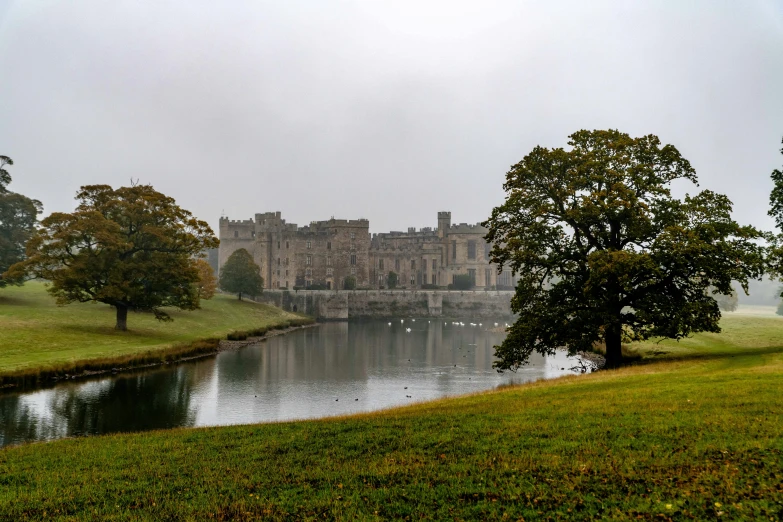 a castle next to the water surrounded by trees