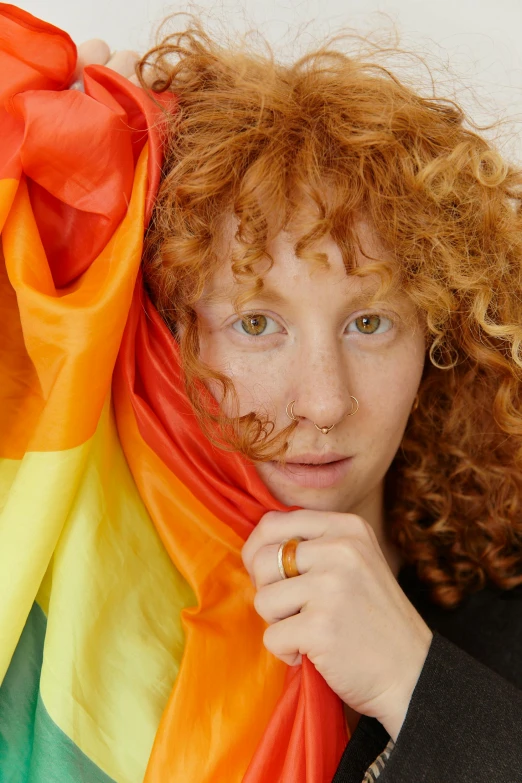 a young woman wearing an orange nose ring, holding a colorful scarf