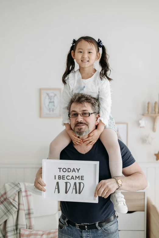 a man carrying a girl while holding a sign that says today i belong away