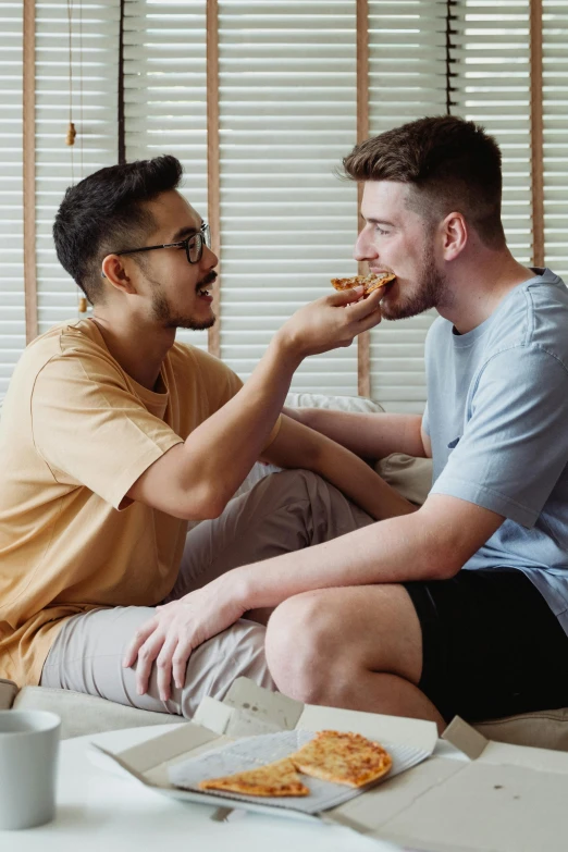 two guys eating pizza in the living room