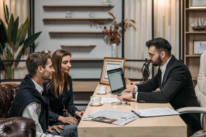 a couple of people sitting around a table with a laptop