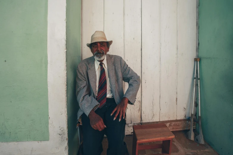 a man in a white hat is standing against a wall