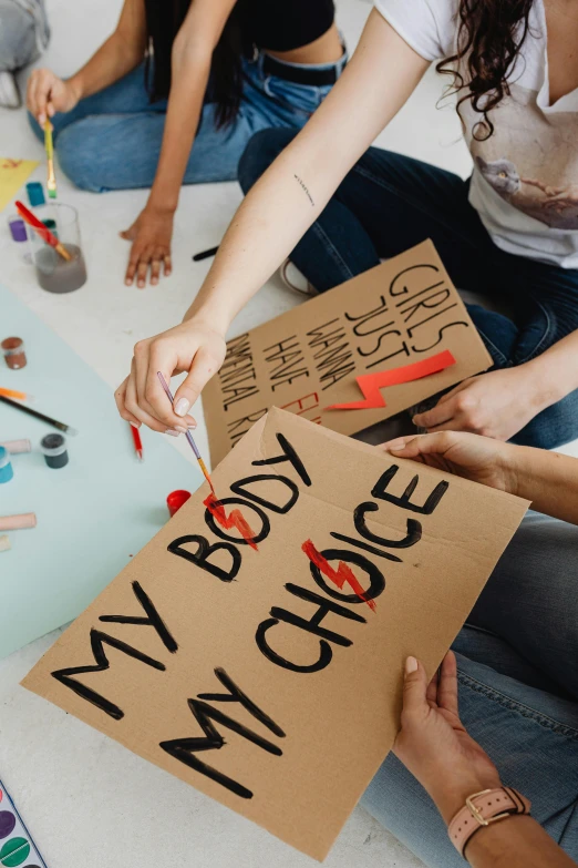 group of people sitting on the floor with signs