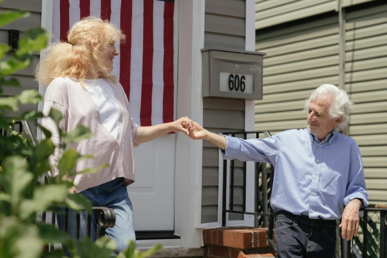an old woman greeting an older gentleman on his porch