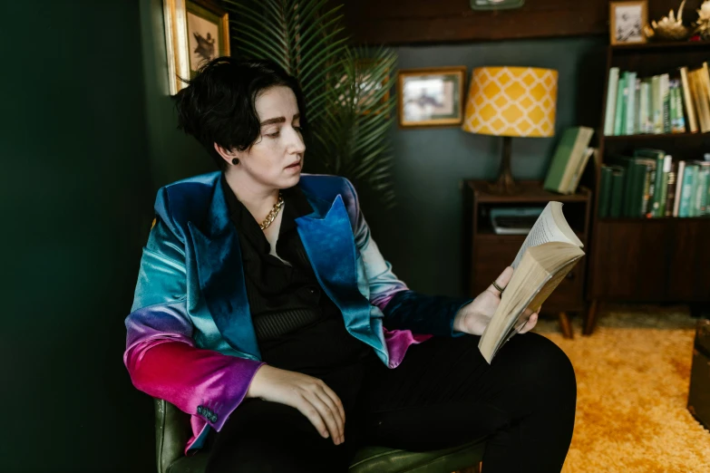 a woman sitting in a chair while reading a book