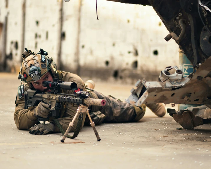 an armed soldier lying on the ground with a weapon