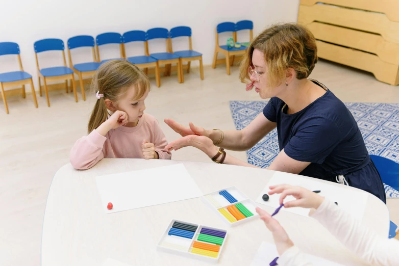 an older woman helps a little girl do color