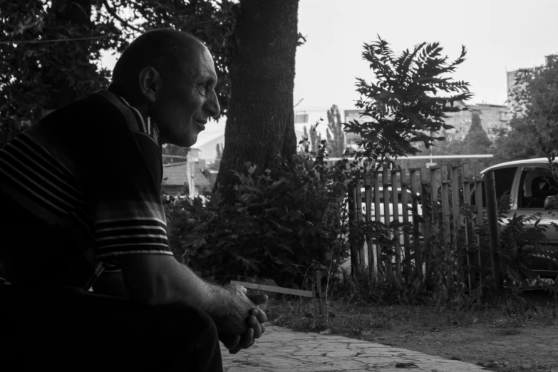 a man sitting on the ground near a tree in black and white