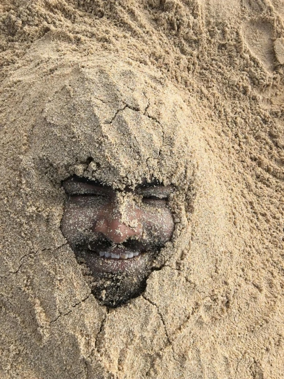 a man's face peeking out of the sand