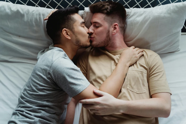 two people kissing while laying in bed