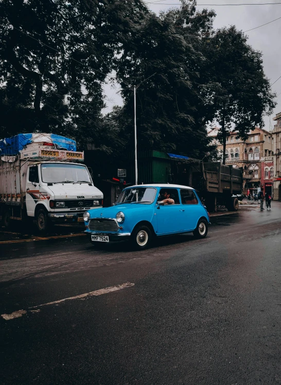 an old, blue car is parked next to another truck