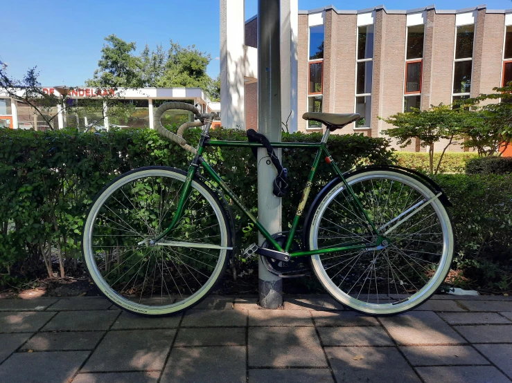 green and white bike parked in front of a pole