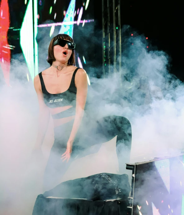 a woman on stage with smoke and bright lights