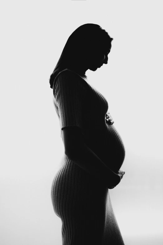 a pregnant woman is in silhouette in a dress