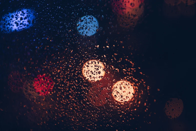 some colored lights behind a wet glass window