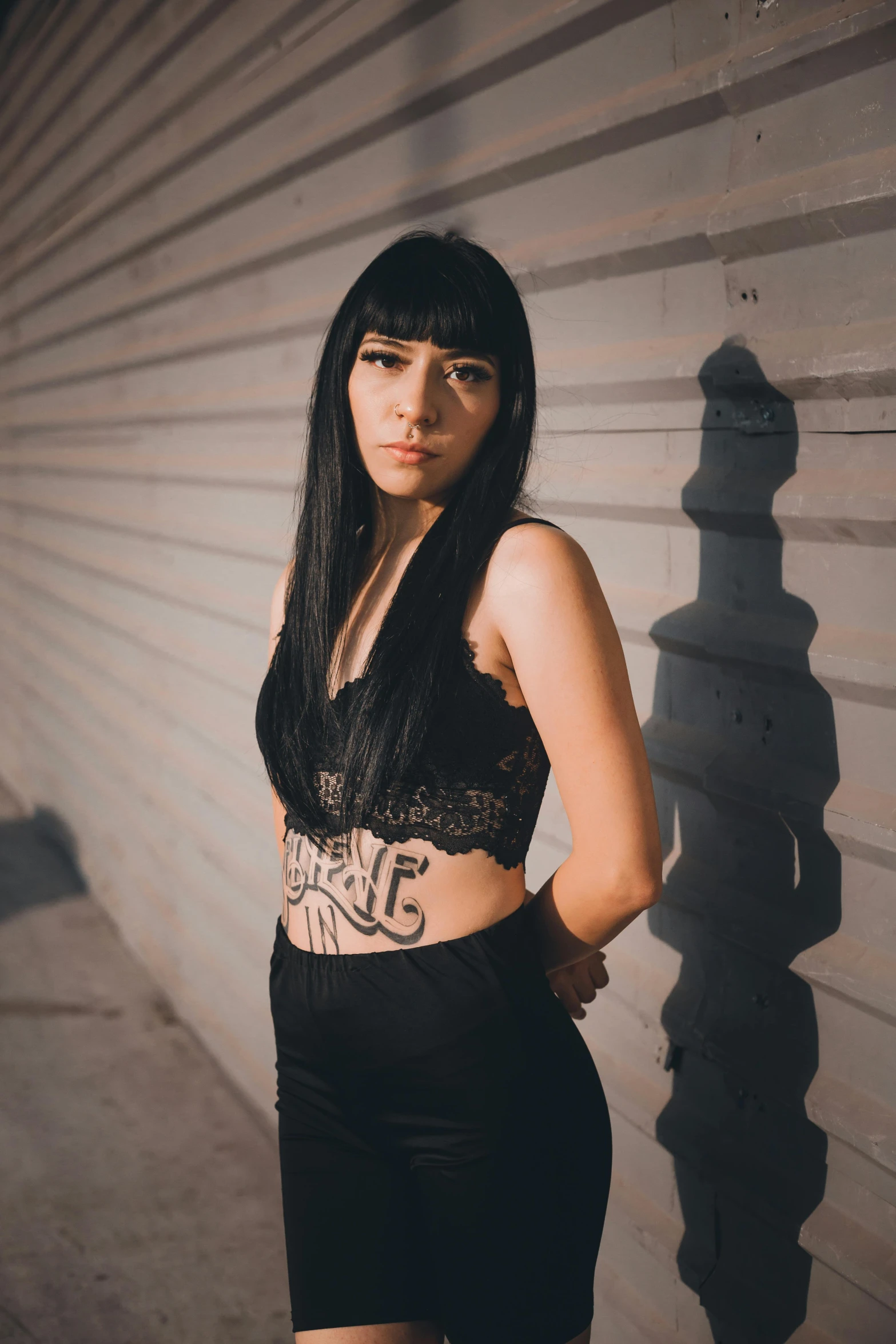 young woman with long dark black hair standing in front of wall