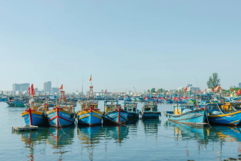 many colorful boats are in the water with buildings in the background