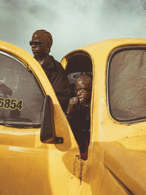 a man leaning out the back window of a yellow car