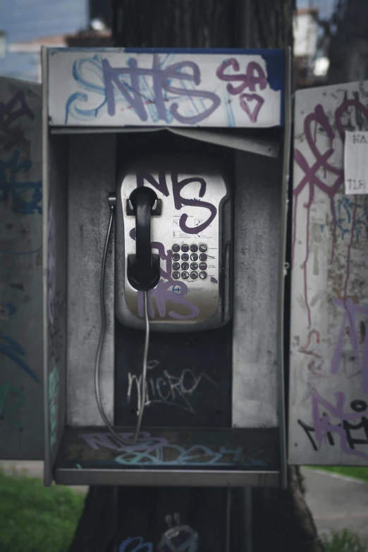 an old style telephone box with a few cellphones inside