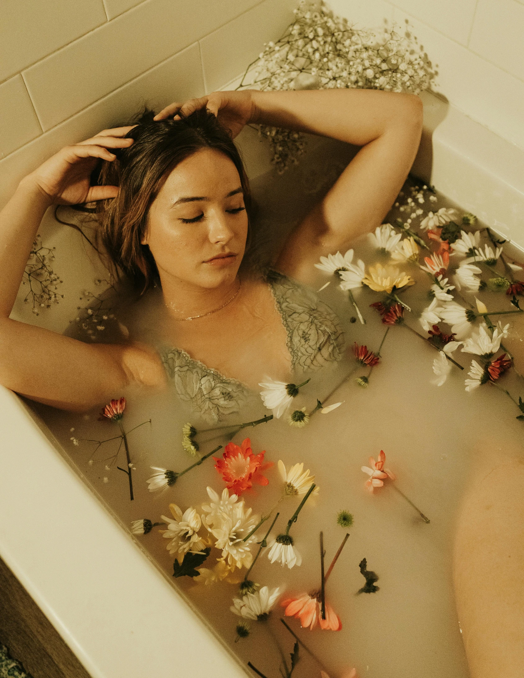 a person in a bath tub surrounded by flowers