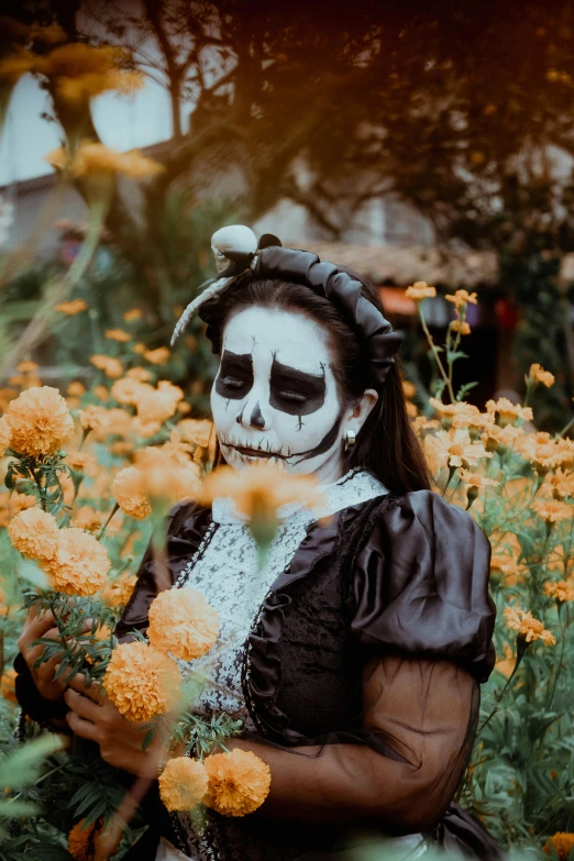 a girl dressed as a skeleton posing in a flower garden