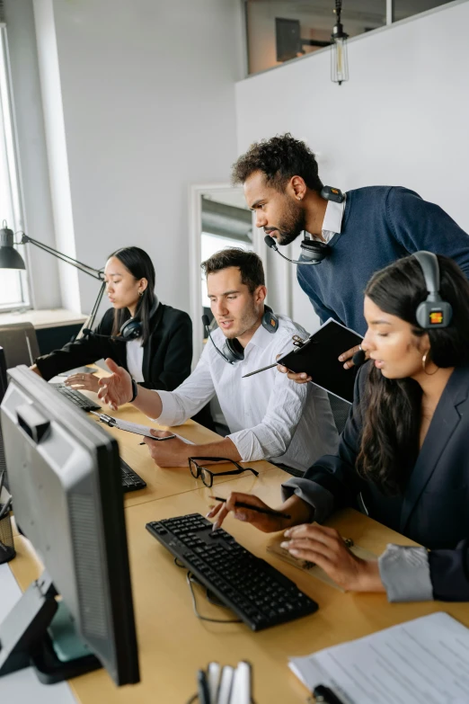 several people at a desk in front of monitors