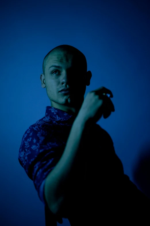 a young man looks into the camera in blue light