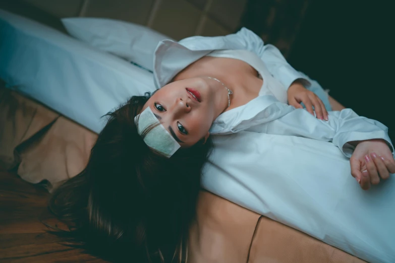 a woman lays down on the bed and covers her face with a mask