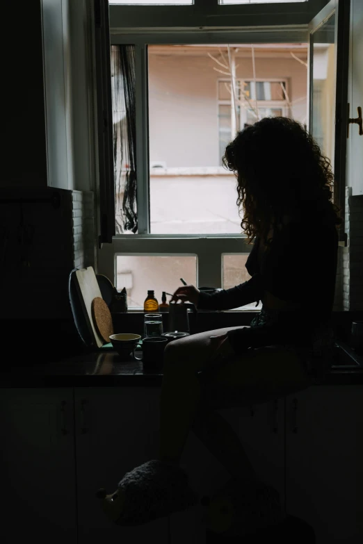 a woman working at her computer in a dimly lit kitchen