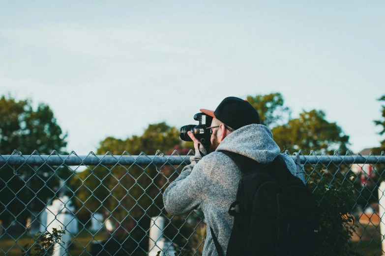 a man taking a pograph through a fence