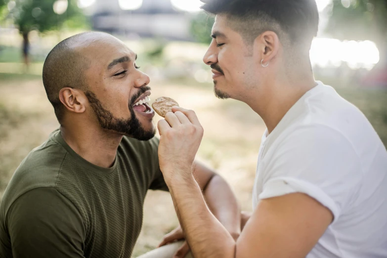 two men one eating an apple while the other looks at him