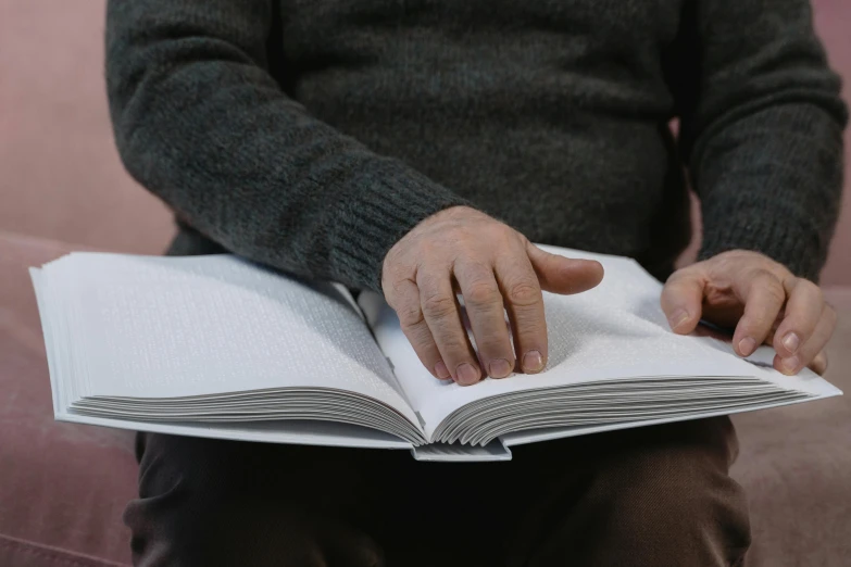 the man is sitting on the couch reading the book