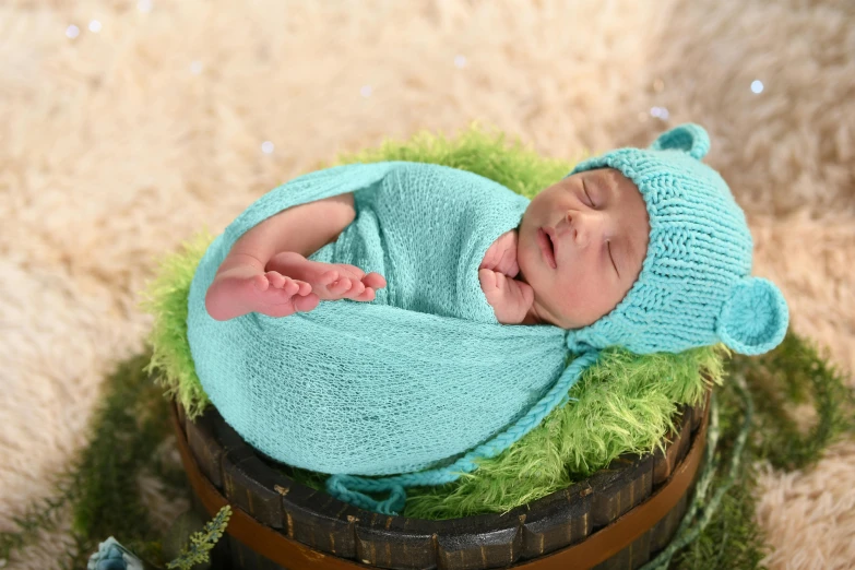 a baby wrapped in green is laying on a barrel