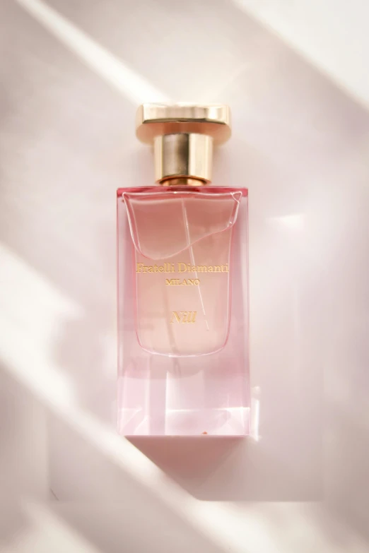 a pink bottle is shown with a gold top