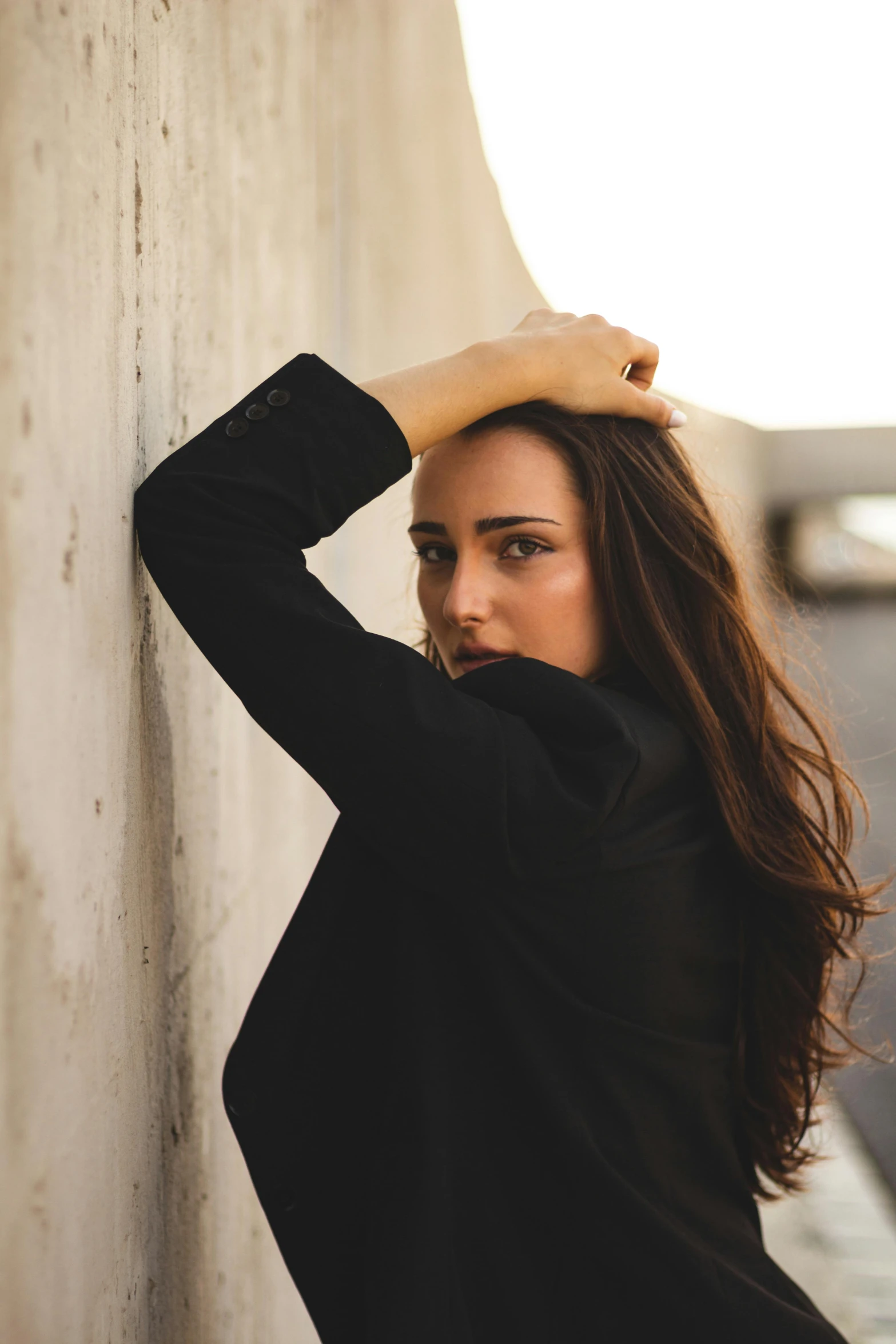 a beautiful young woman posing by a wall