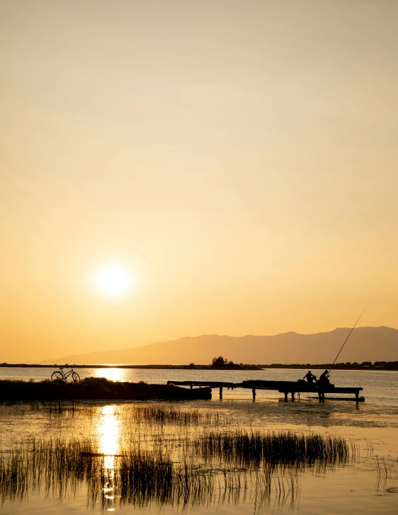 a person fishing in a lake at sunset