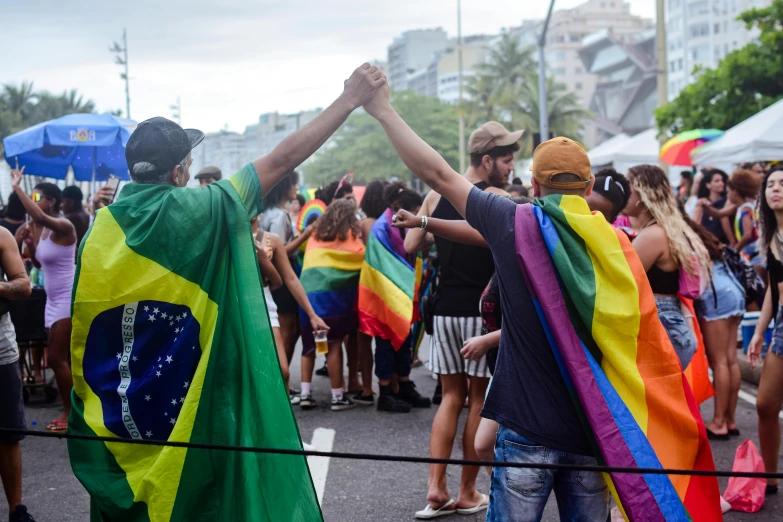 people holding hands and flags are dancing down the street