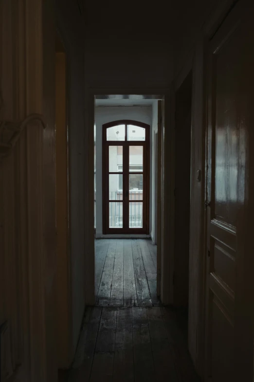 an empty hallway with door, window and wooden floor