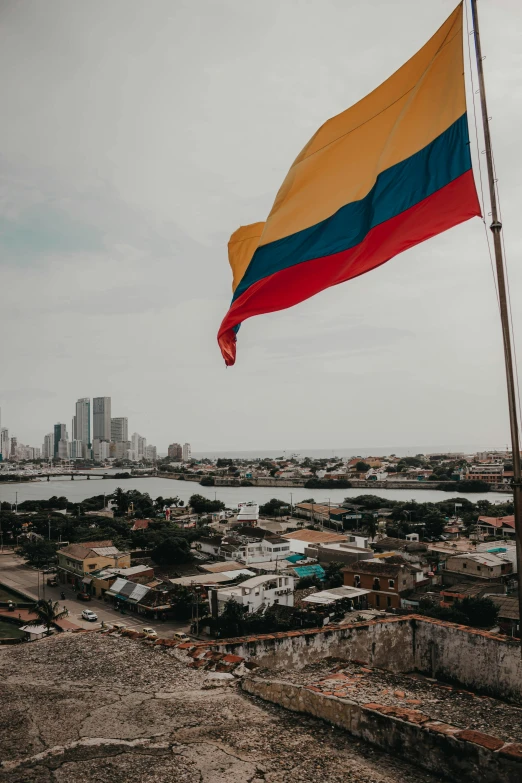 a flag is flying in a gray, cloudy sky over a city