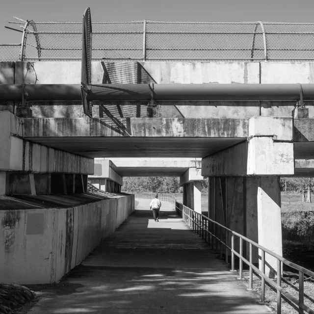 a woman is walking under a highway bridge