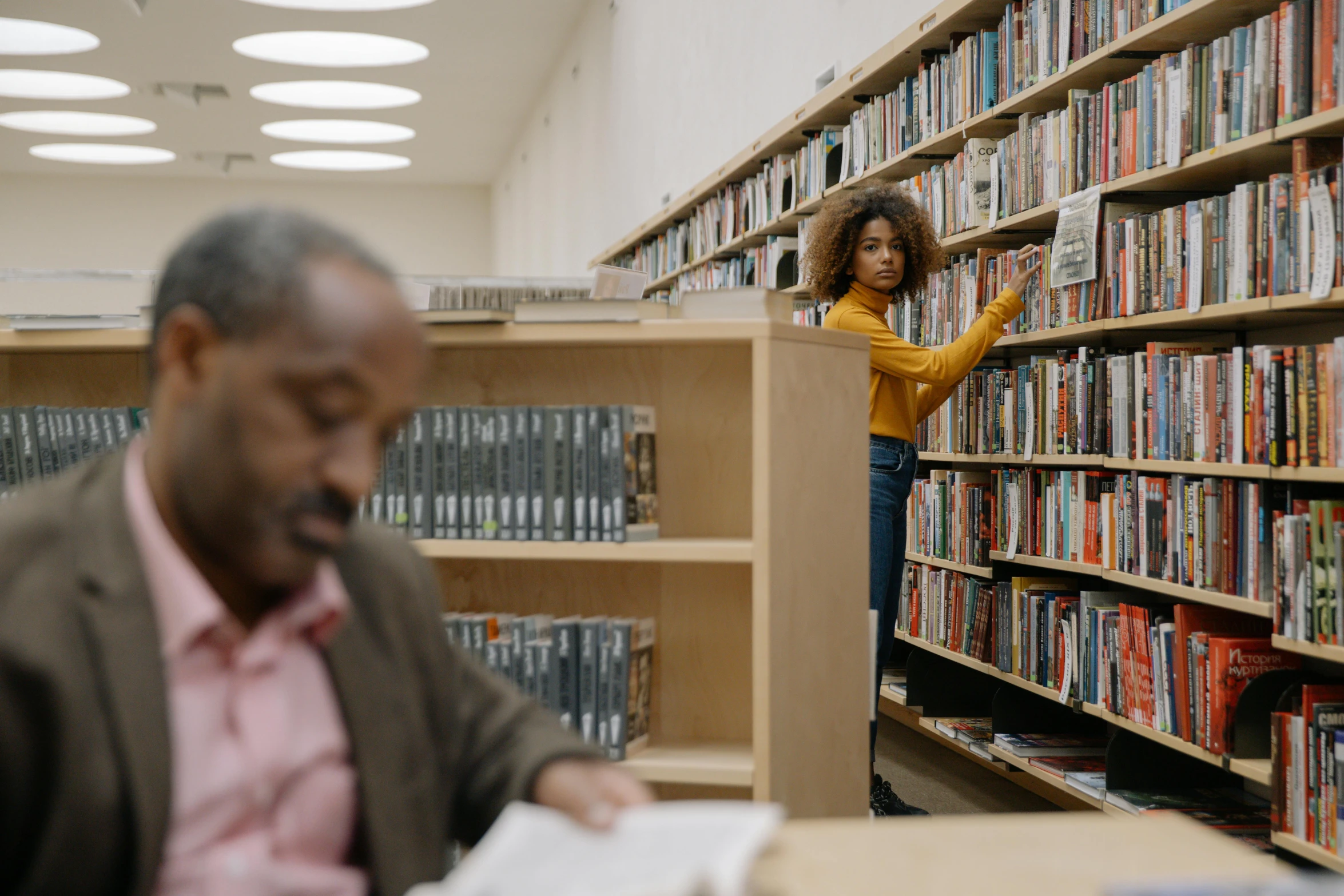 an african american man standing in front of a large book shelf filled with books