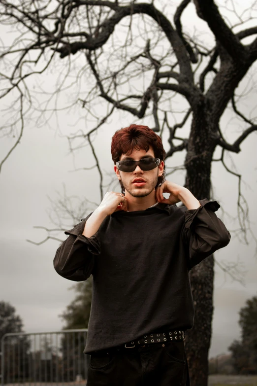 a man with glasses is posing under a tree