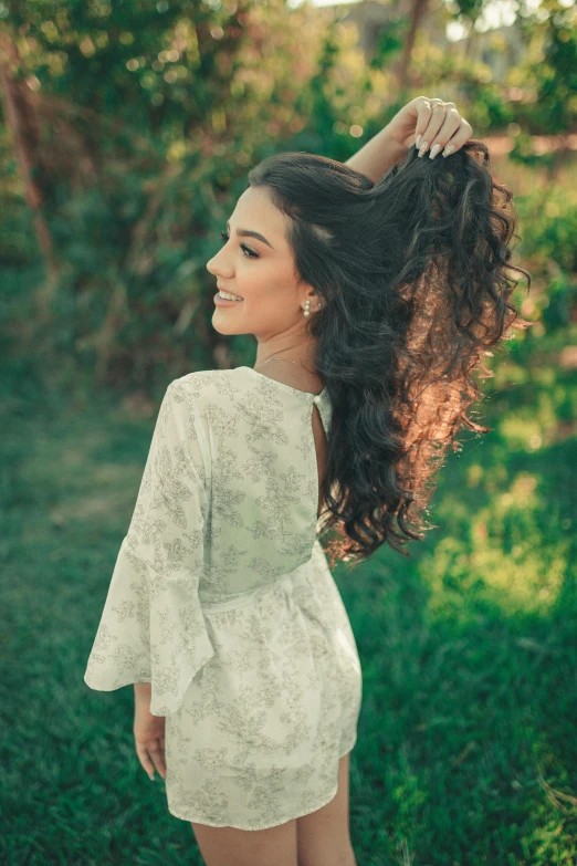 a beautiful young lady standing in a field, brushing her hair