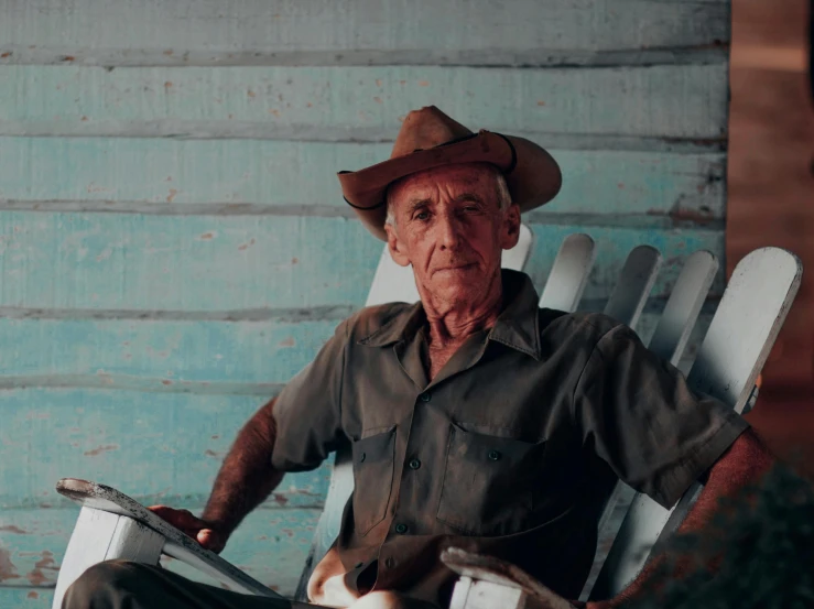 an old man sitting on a white chair next to a blue building