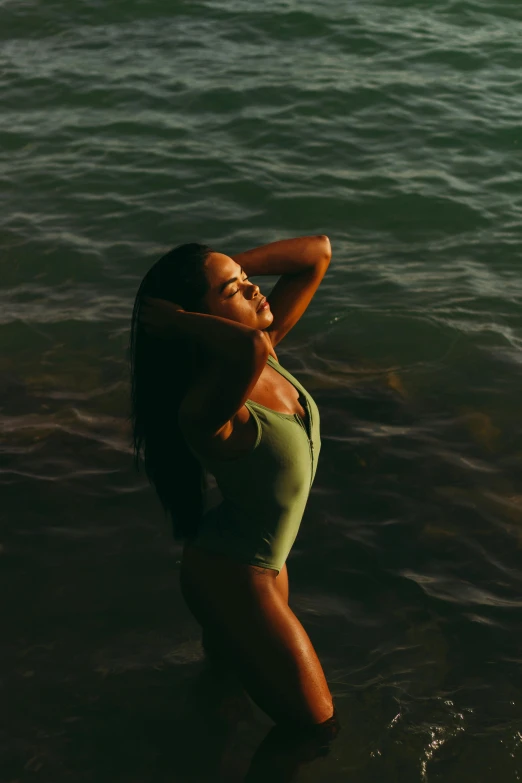 a woman in a green bathing suit standing in water