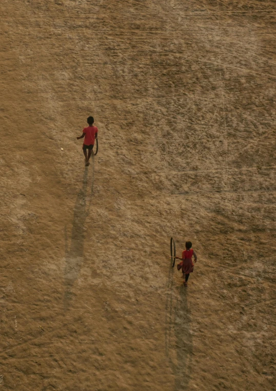 there are two small boys walking through the dirt