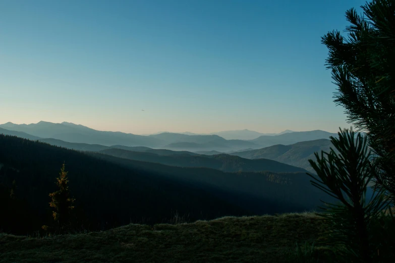 a view looking down at mountains, trees and clouds